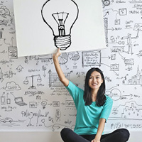 Woman holding up a drawing of a light bulb to signify an idea