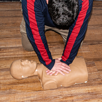 Someone doing CPR on a mannequin
