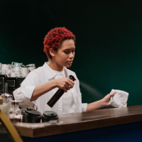 Woman cleans bar top with spray and cloth