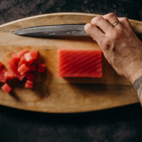 Person preparing salmon on a wooden board