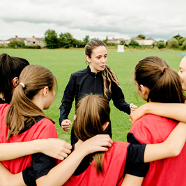 A female sports coach speaking to a group of athletes
