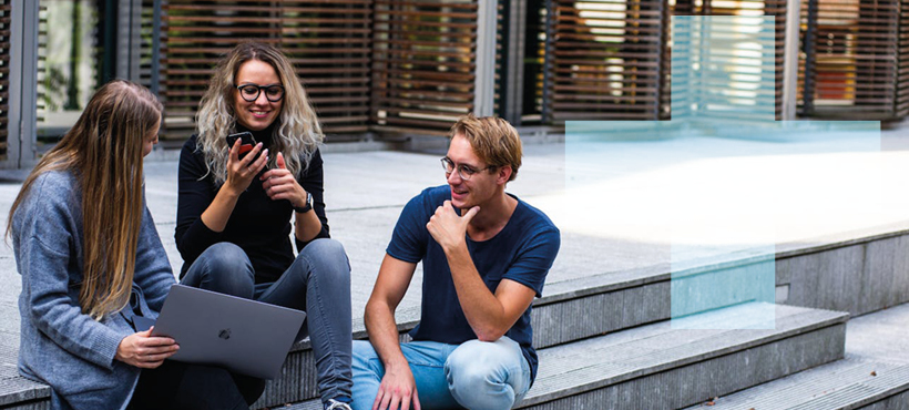 3 students sitting on steps outside chatting