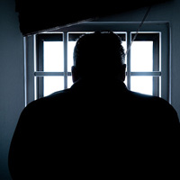 Shadow of man looking out of prison window