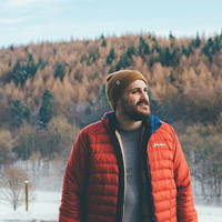 Man standing in snowy field with a red jacket on