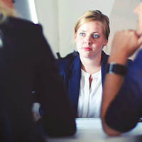 Woman speaking to 2 people at a table