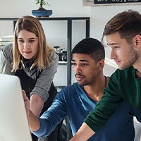 Group of office workers gathered around a computer making decisions