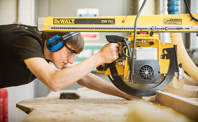 Student wearing PPE cutting lengths of wood using a circular saw Student wearing PPE cutting lengths of wood using a circular saw
