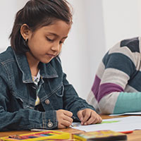 Girl at school drawing with crayons