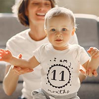 Childcare provider helping toddler stand up